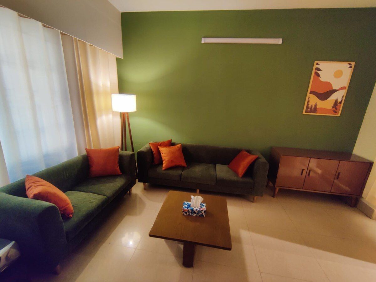 Living room Green sofa with rust cushions against a sage wall