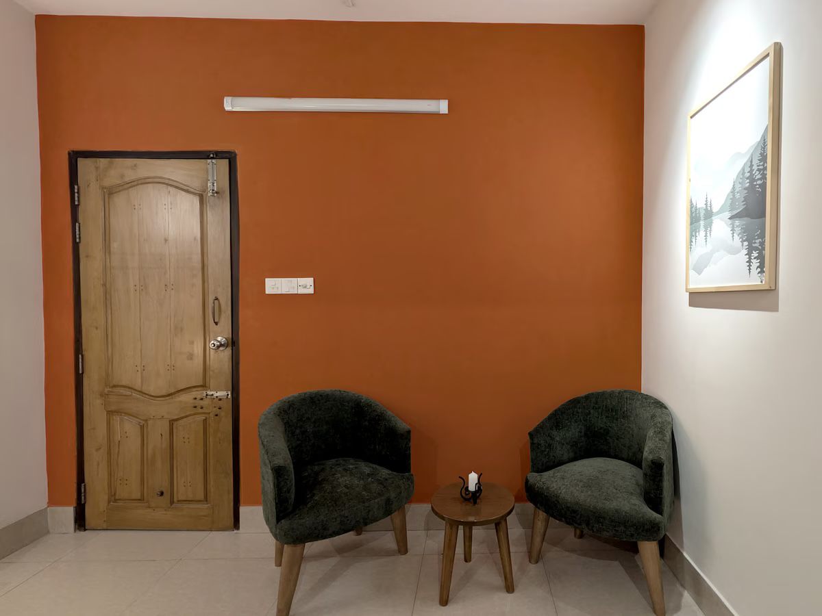 Two green armchairs against a terracotta wall